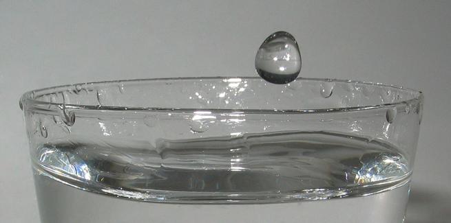 Uma gota d'�gua caindo na �gua em um copo